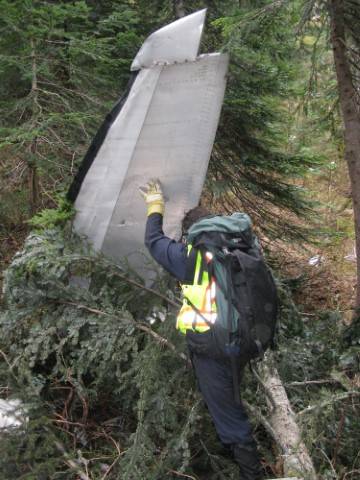 Photo of an investigator and the right horizontal stabilizer on site after snow melted