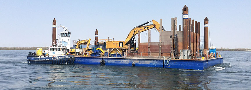 Barge with tugboats shown working at the sides