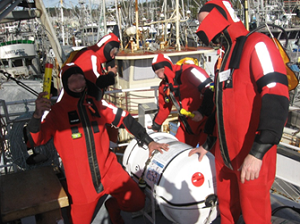 Four fishermen wearing immersion suits muster at their liferaft during an industry drill day in Comox, BC