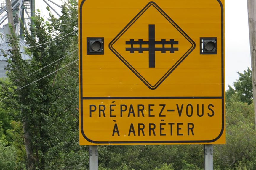 A 'Prepare to Stop at Railway Crossing' sign with flashing lights on Highway 347 in Saint-Norbert, Quebec