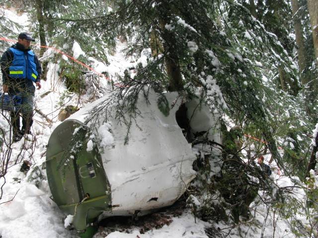 Photo of the wreckage of investigators with the aircraft's nose section at the accident site