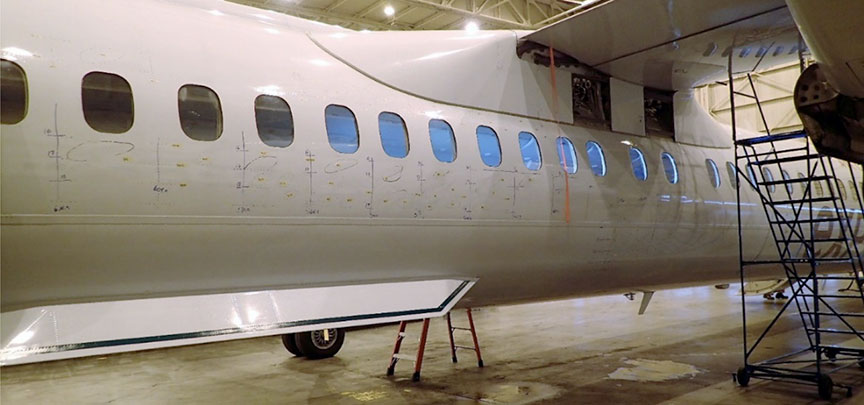 Maintenance marks on the right-side fuselage showing areas of buckling