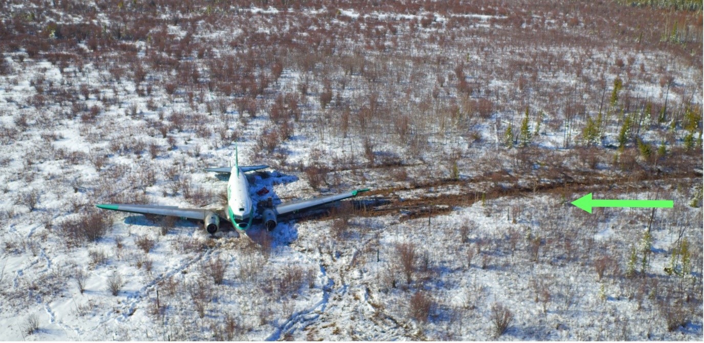 Aerial photo of the accident site looking northwest. The green arrow indicates the aircraft’s path on touchdown. (Source: K'atl'Odeeche First Nation, with TSB annotation)