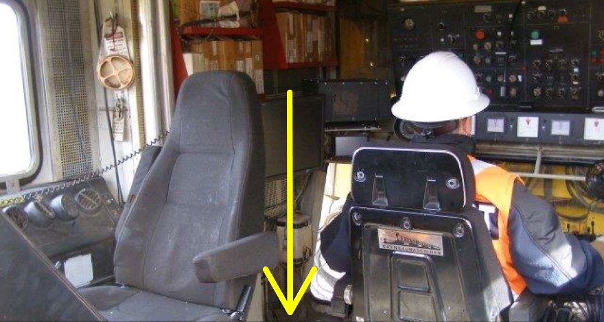  Demonstration of how the operator trainee would have been seated at the controls at the time of the occurrence. The operator trainee would be facing east. The operator trainer was standing behind the empty seat in the position indicated by the arrow, beside the operator trainee (Source: TSB)