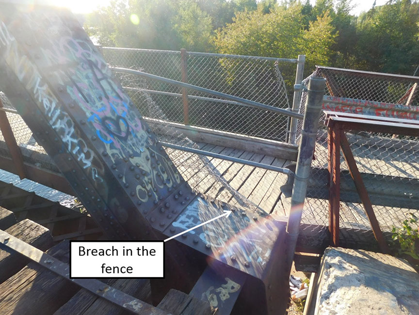 Breach in the fence of the walkway at the northeast end of the railway bridge