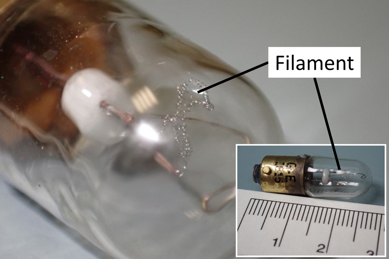 Figure 4. Enlarged view of the filament from the lightbulb removed from the occurrence aircraft’s stall warning system, with full view of the lightbulb in inset (scale reference in cm) (Source of images: TSB) Figure 4. Enlarged view of the filament from the lightbulb removed from the occurrence aircraft’s stall warning system, with full view of the lightbulb in inset (scale reference in cm) (Source of images: TSB)